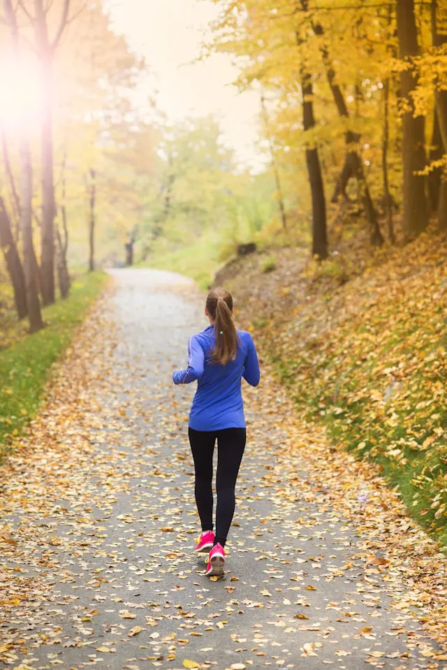 Person jogging in a scenic park, symbolizing the benefits of not watching TV.