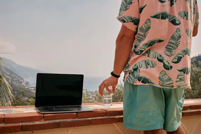 Man working on a laptop with a picturesque sea view in the background