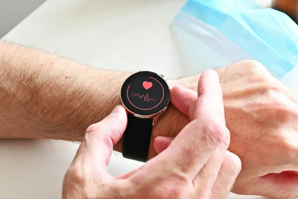 Close-up of a smartwatch on a man's wrist displaying heart rate with a heart symbol.