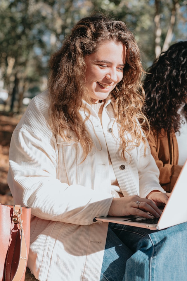 Woman ensuring Vitamin D intake through sunlight working on her laptop outdoors