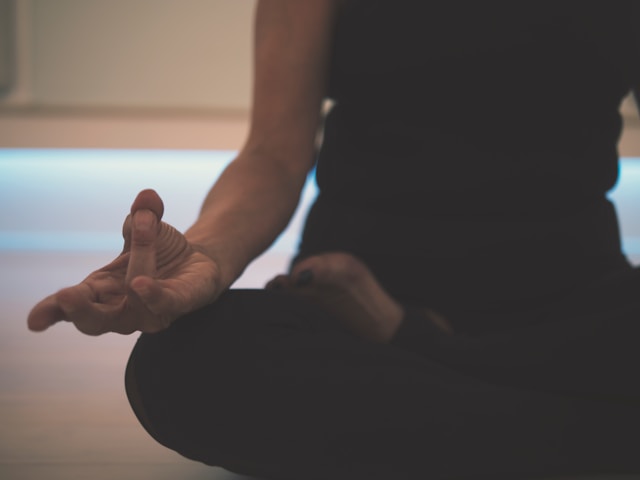 A person sitting cross-legged practicing meditation in a dimly lit room