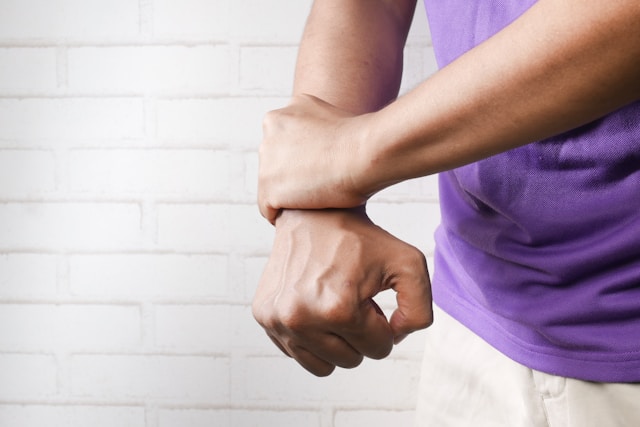 A close-up of a person's hands pressing on their swollen wrist, highlighting the inflammation.