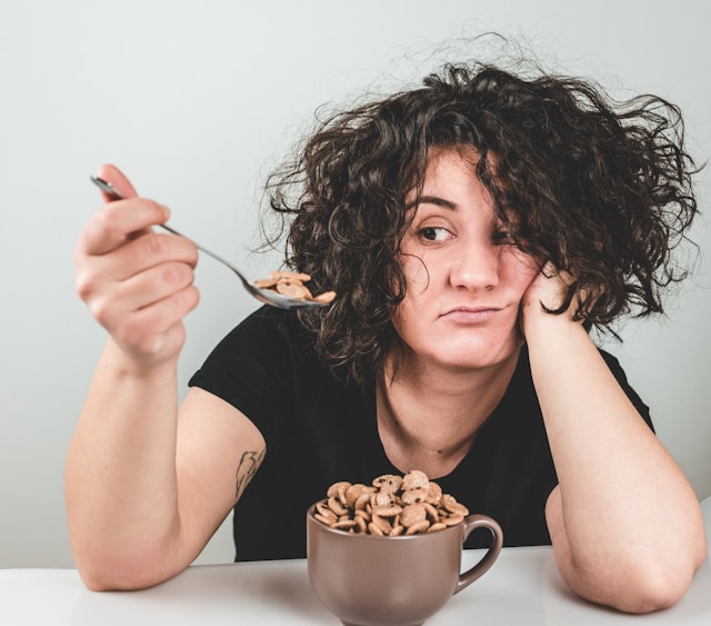 woman-with-messy-hair-wearing-black-crew-neck-t-shirt-holding-spoon-with-cookie cereal