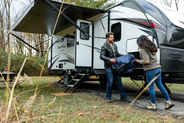 Couple setting up campsite next to their RV with essential RV items