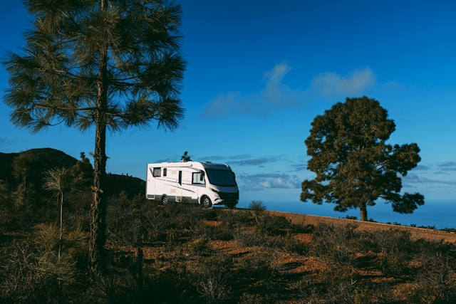 RV parked on a scenic hilltop with trees, showcasing free overnight parking for RVs in nature