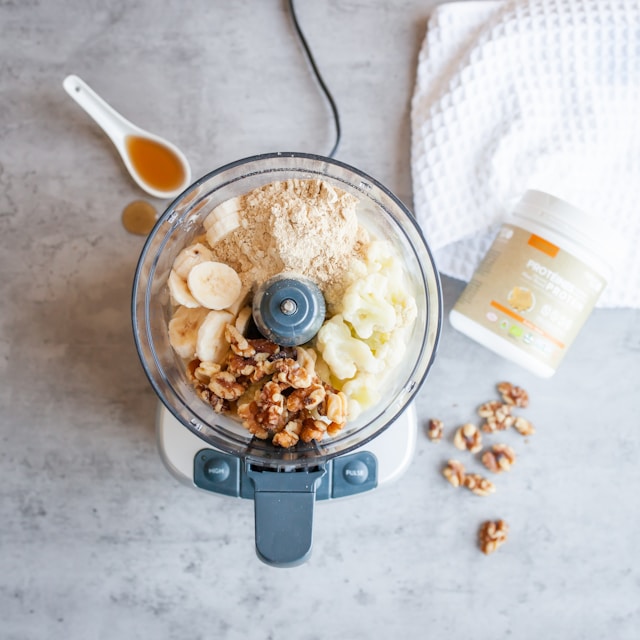 Blender with ingredients for a morning smoothie and a supplement bottle, representing all-in-one vegan supplements.