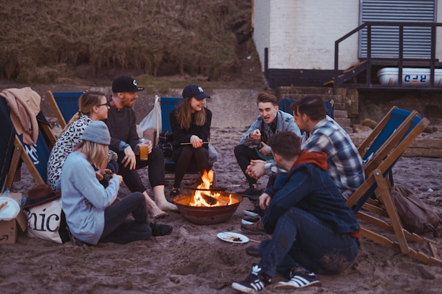 Group of friends sitting around a bonfire on a beach.