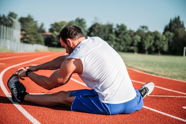 Man stretching on a running track, preparing for exercise.