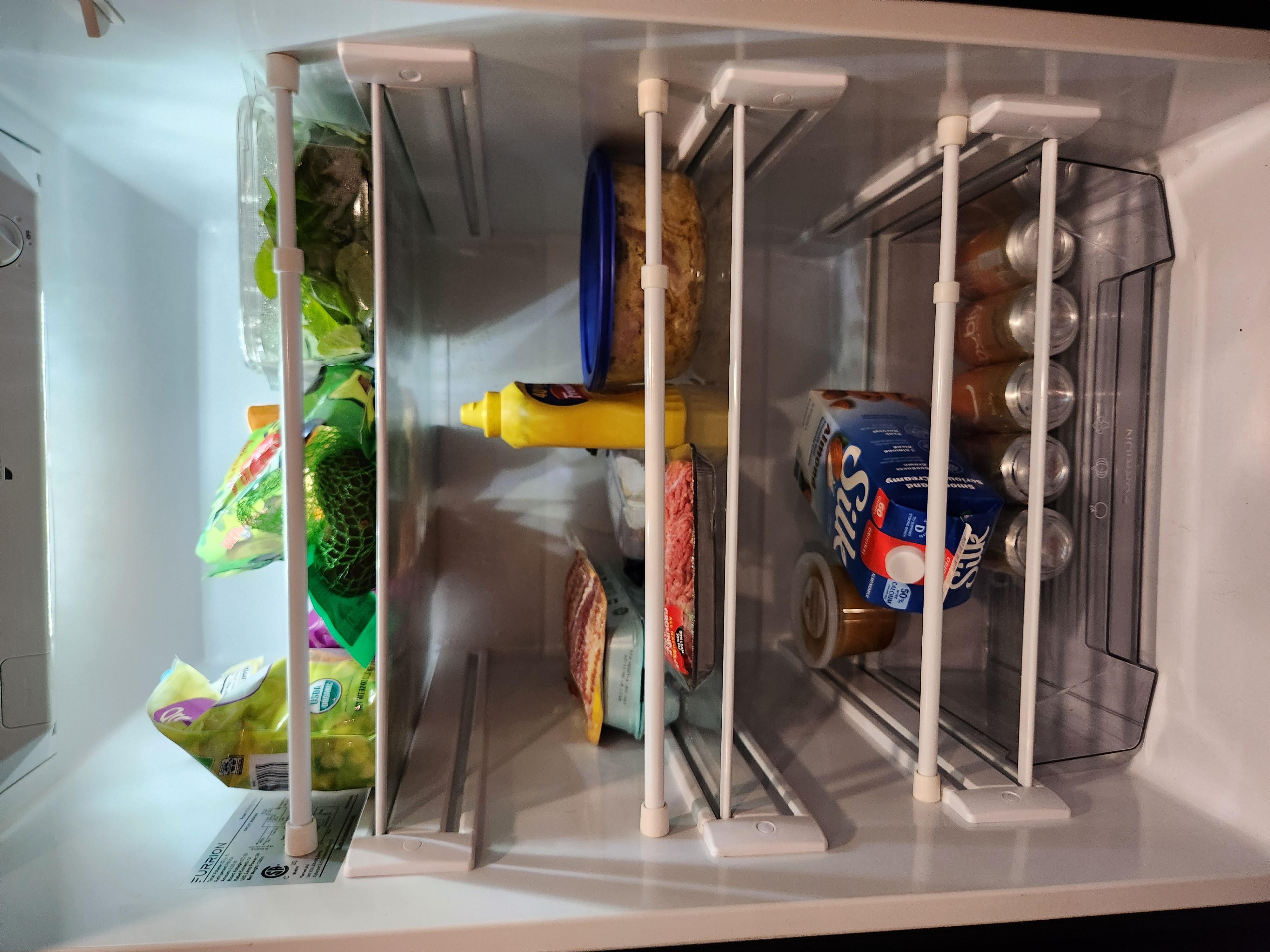 Well-organized RV fridge with vegetables, condiments, and other food items neatly arranged on shelves.