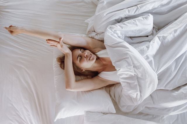 Young woman stretching in bed, depicting the improvement in sleep quality and energy from regular acupuncture sessions.