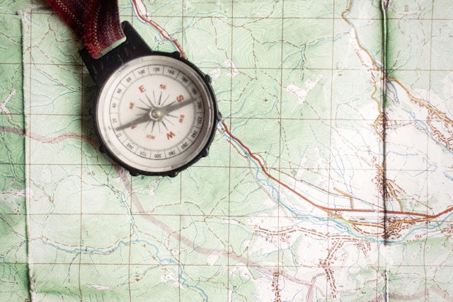 An old-fashioned compass resting on a detailed topographic map, highlighting essential navigation tools for hiking.