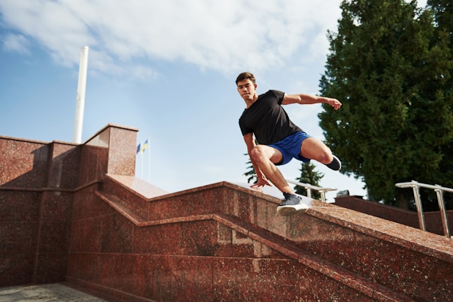 A man in athletic wear performing parkour on a staircase outdoors, showcasing agility and fitness.