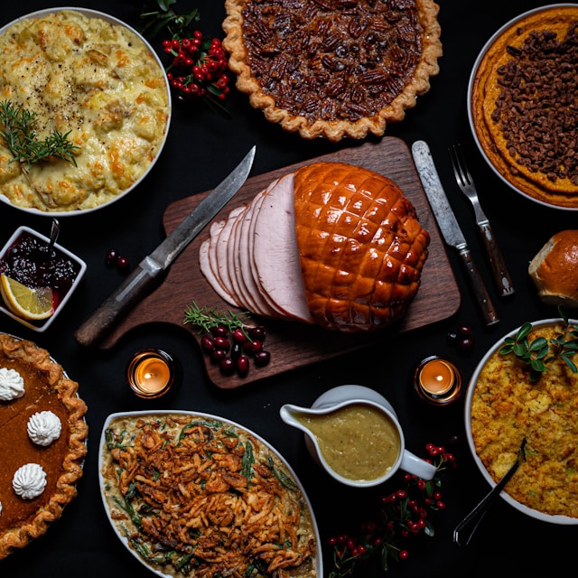 An elaborate dinner setup featuring turkey, pies, and assorted side dishes on a dark background.