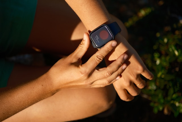 Close-up of a runner's hands adjusting a smartwatch, emphasizing technology's role in tracking fitness progress.