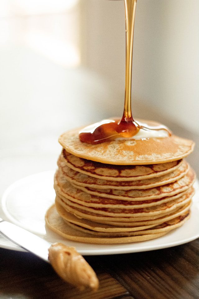 Golden pancakes stacked high, drizzled with amber maple syrup, highlighting a classic breakfast treat.