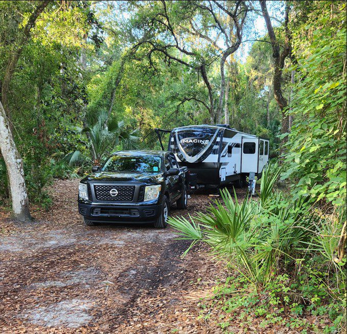 Rob's truck and travel trailer in a lush, Florida campsite.