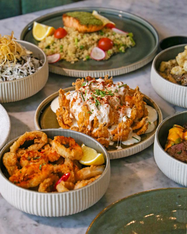 A variety of seafood and chicken dishes elegantly presented in ceramic bowls on a marble countertop.