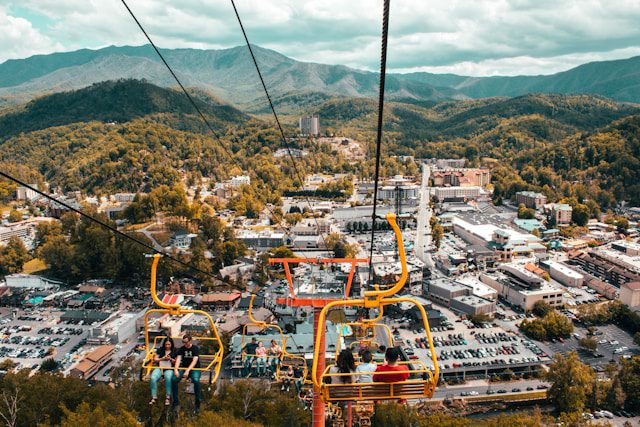 Vibrant aerial view over the Smoky Mountains and Pigeon Forge, featuring people riding a chairlift above the town.