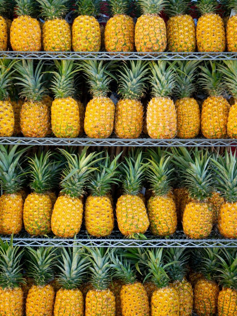 Rows of ripe pineapples stacked neatly at a Hawaiian market, showcasing their vibrant yellow colors.