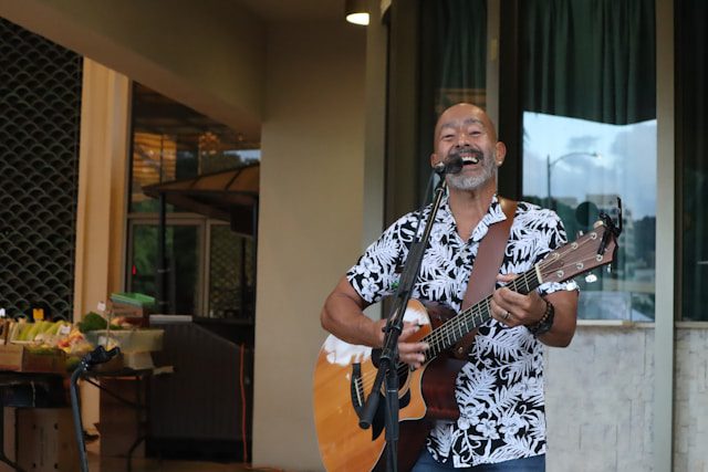 Smiling street musician playing guitar outside a cafe