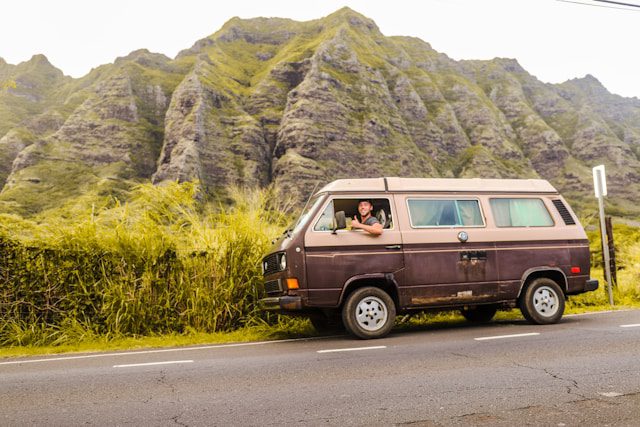 Van parked on a roadside with lush green mountain backdrop