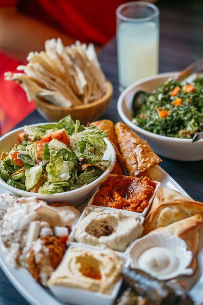 A vibrant Mediterranean meze platter with hummus, pita bread, salads, and assorted dips on a colorful table setting.