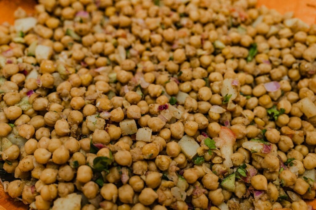 A close-up view of seasoned chickpeas mixed with herbs and diced vegetables, perfect for a flavorful, nutritious meal.
