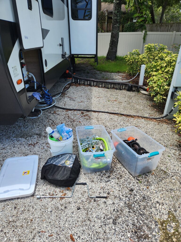 Clear tote storage solutions for RV travel trailers next to a travel trailer with the pass-through storage door open.